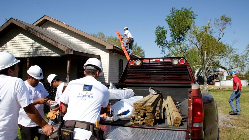 Roofing crew unloading lumber for tarp repairs after a hurricane in Texas