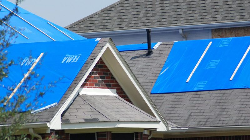 Blue tarps covering storm-damaged roofs on a brick home after Hurricane Ike in Texas