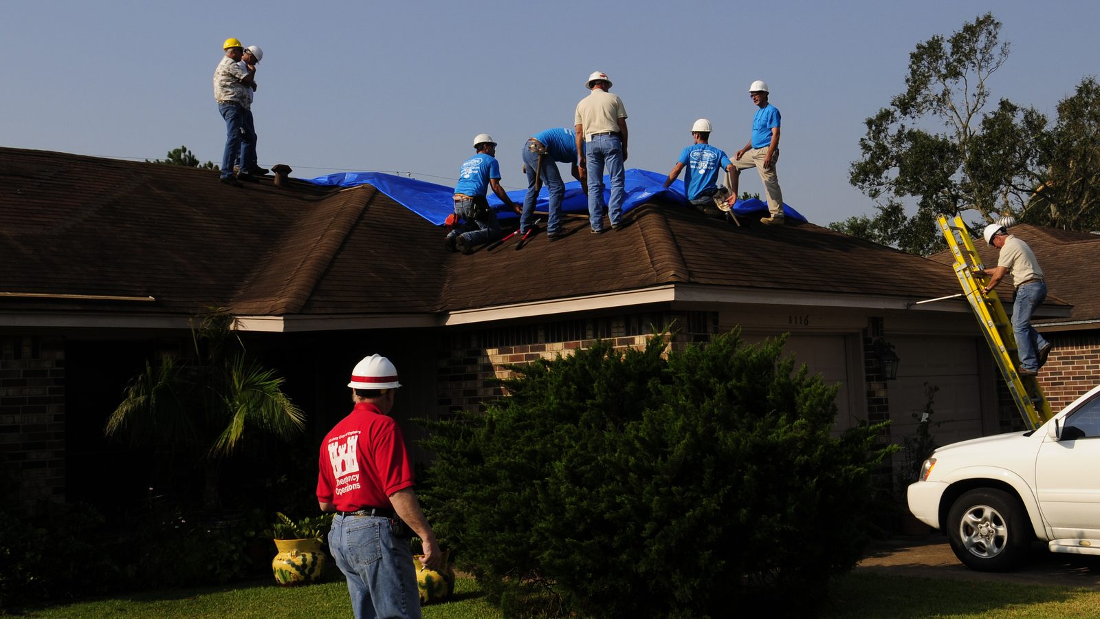 Crews installing a blue tarp on a Houston home after Hurricane Ike