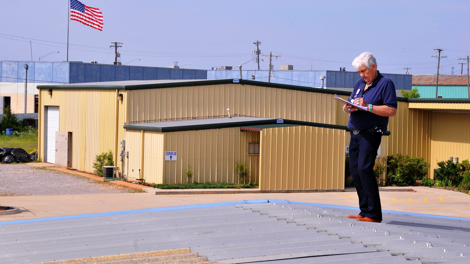 Inspector recording hail damage on a roof with a clipboard