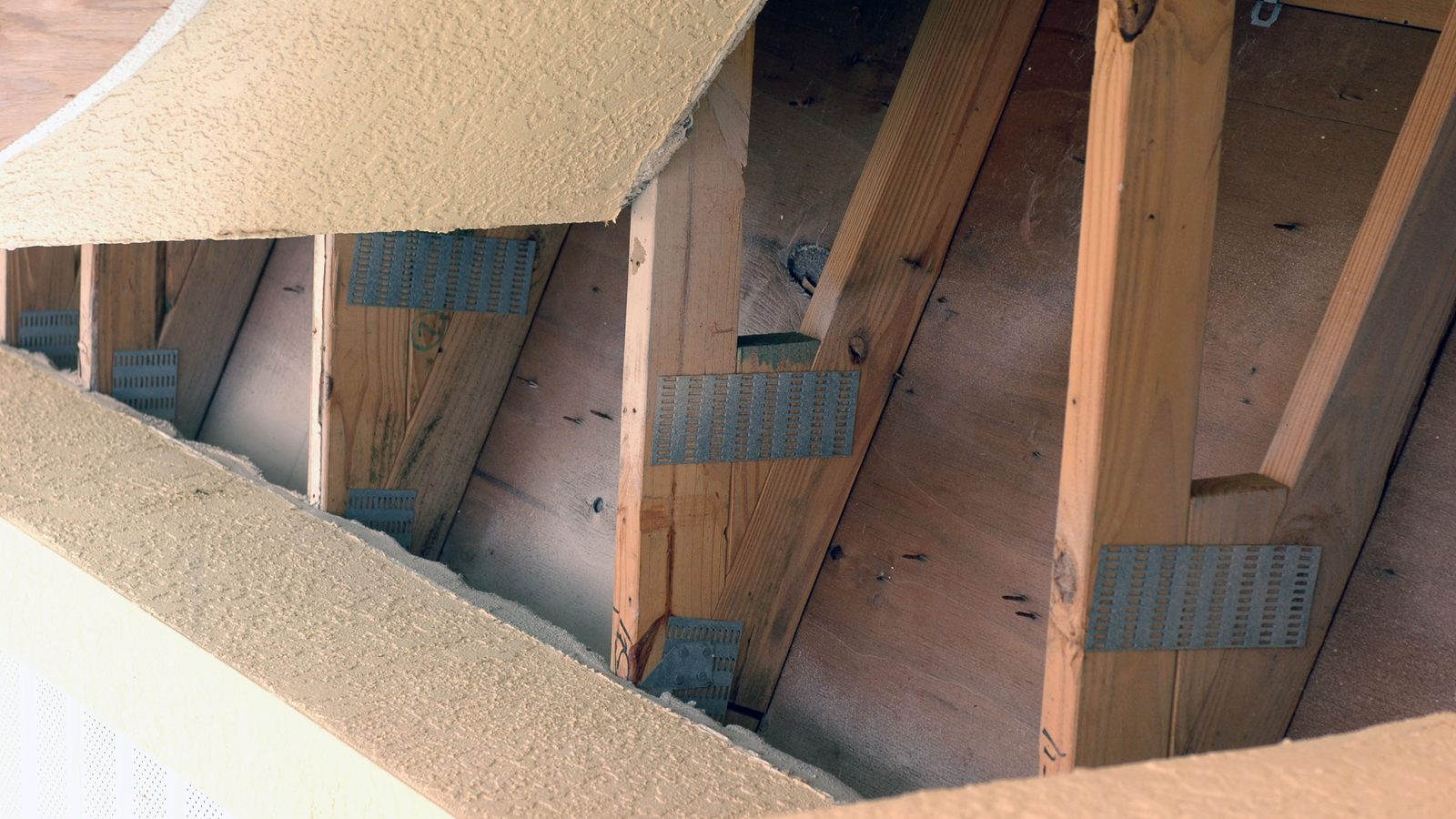 Metal hurricane straps tying roof rafters to the wall framing