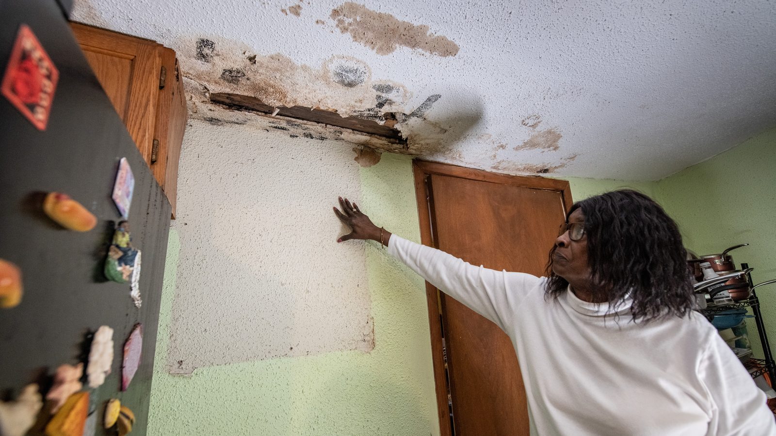 Homeowner pointing to a water-damaged ceiling from a roof leak