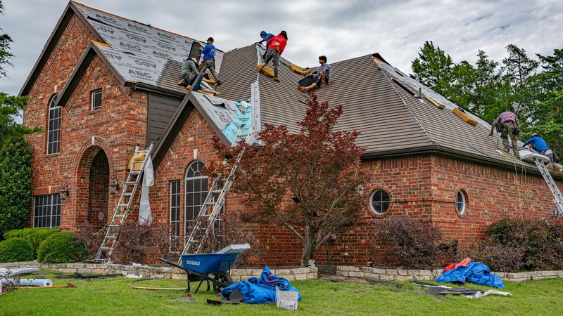 Roofing crew re-roofing a large brick Texas home with tarps protecting the yard — Installation Day